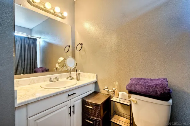 a bathroom with a granite countertop sink a toilet and a mirror