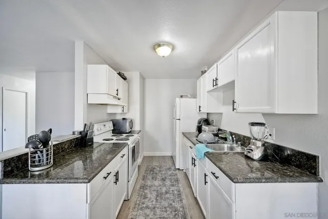 a kitchen with granite countertop a sink stove and cabinets