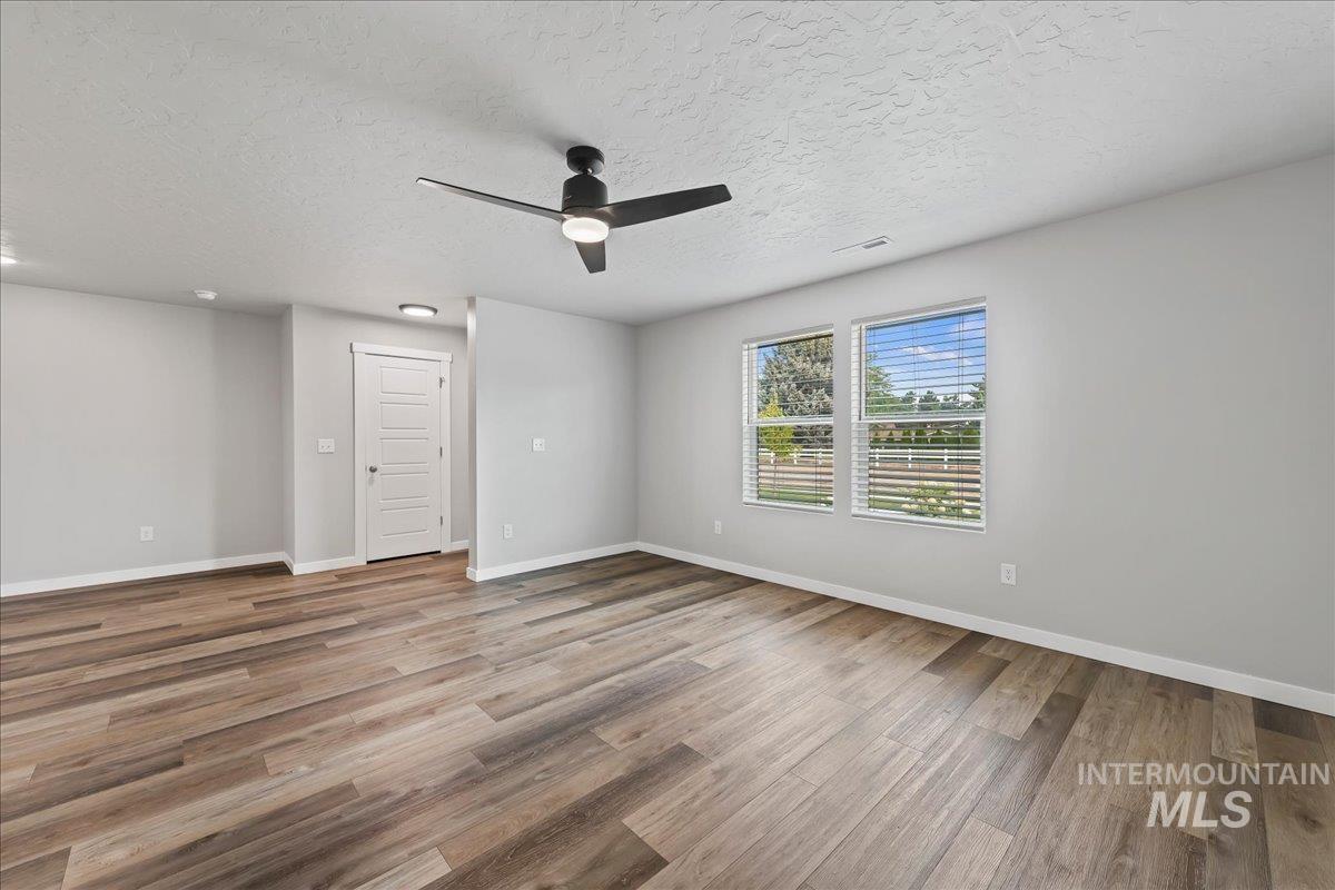 12535 West Victory Road Boise, ID 83709 - Photo 5 of 25 Wood-finish flooring, two large windows with blinds, recessed lighting, and a ceiling fan with integrated light