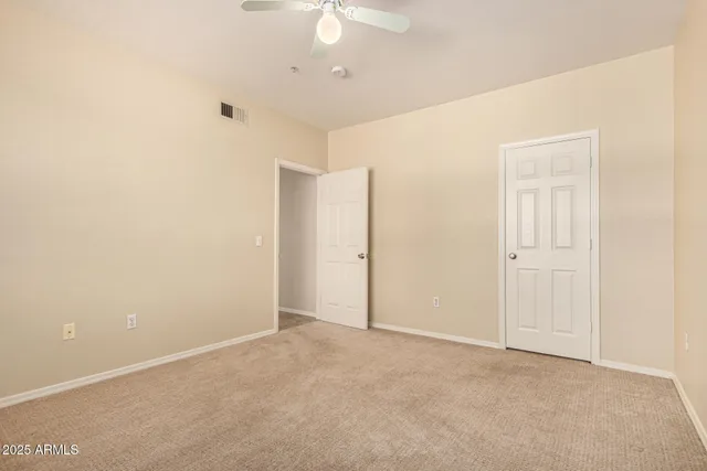 an empty room with a ceiling fan and carpet