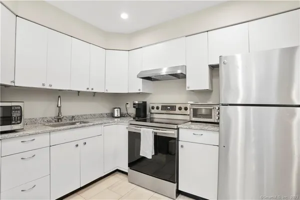 a kitchen with stainless steel appliances granite countertop white cabinets sink and a refrigerator