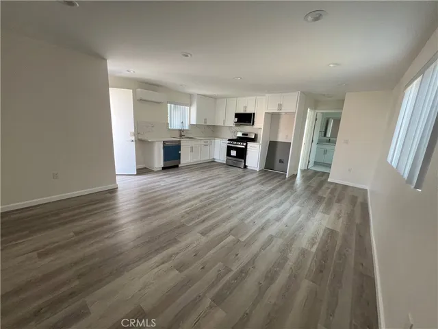 a view of empty room with wooden floor and furniture
