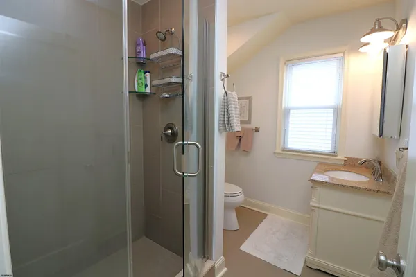 a bathroom with a granite countertop sink a toilet and shower