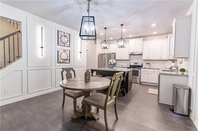 a kitchen with stainless steel appliances kitchen island granite countertop a table chairs in it and wooden floors