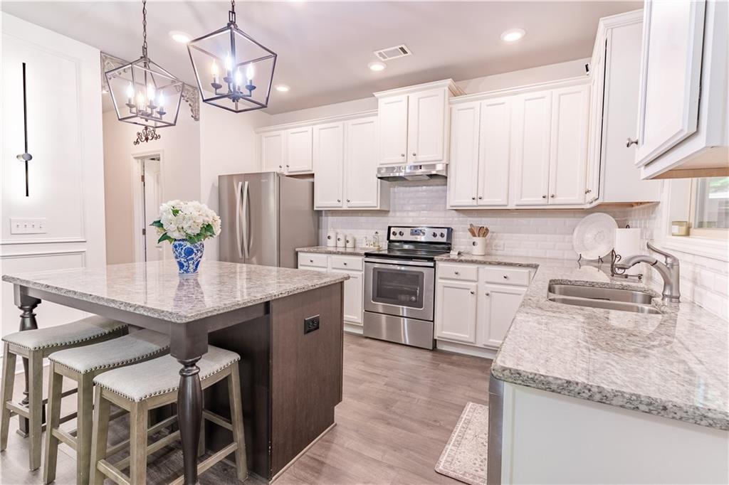 3041 Vista Ridge Braselton, GA 30517 - Photo 16 of 56 a kitchen with stainless steel appliances kitchen island granite countertop a table chairs in it and wooden floors