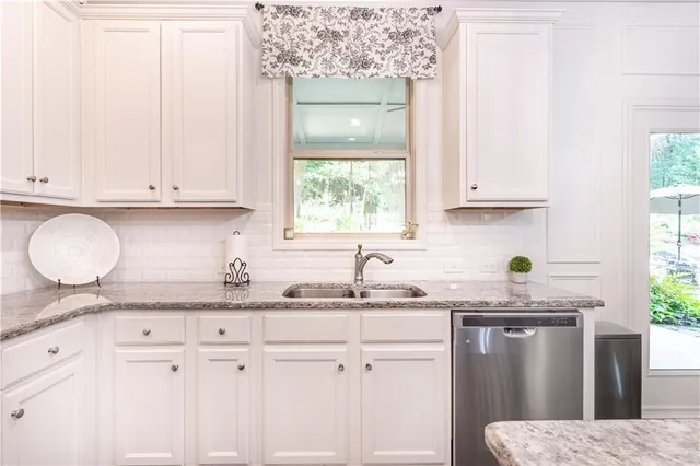 a kitchen with granite countertop a sink stainless steel appliances cabinets and a large window