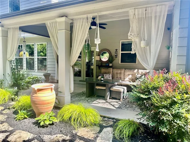 a view of a backyard with chairs and flower plants