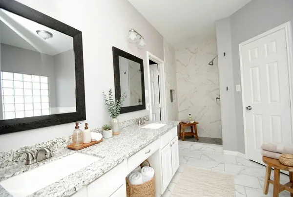 a bathroom with a granite countertop double vanity sink and a mirror