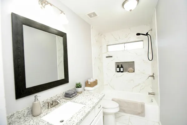 a bathroom with a granite countertop sink a mirror and shower