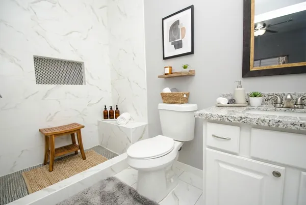 a bathroom with a granite countertop toilet sink and mirror