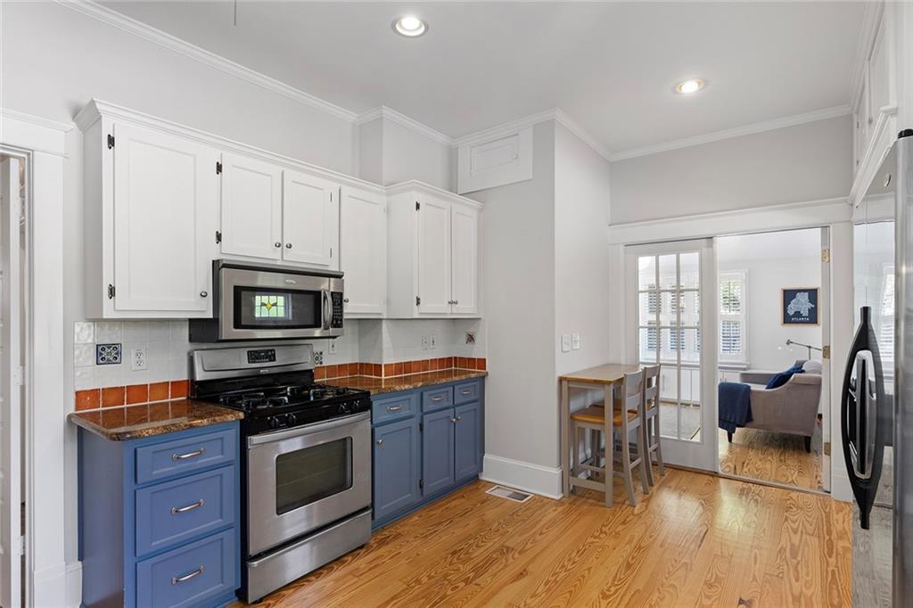 320 Ferguson Street Northeast Atlanta, GA 30307 - Photo 15 of 28 a kitchen with stainless steel appliances a stove top oven a sink dishwasher and white cabinets with wooden floor