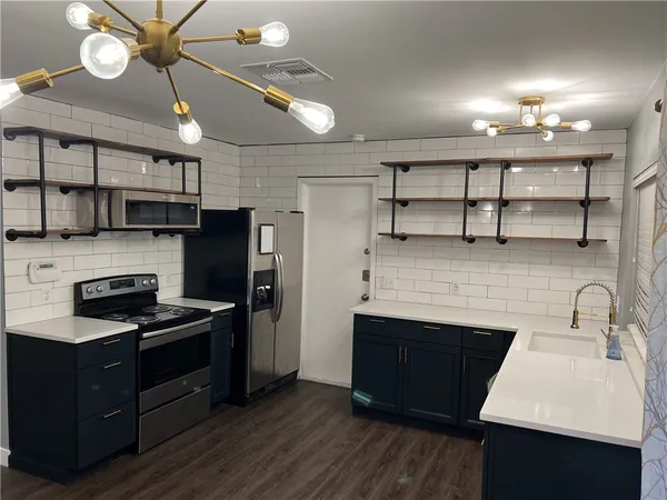 a kitchen with a sink stainless steel appliances a counter space and cabinets