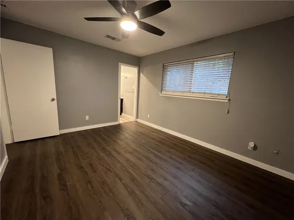 a view of an empty room with wooden floor and a window