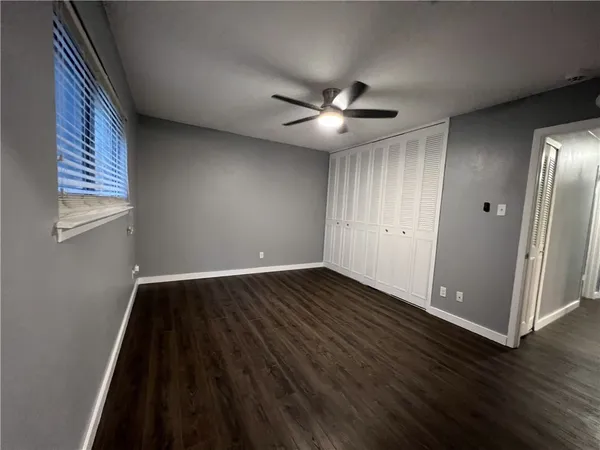 an empty room with wooden floor fan and windows