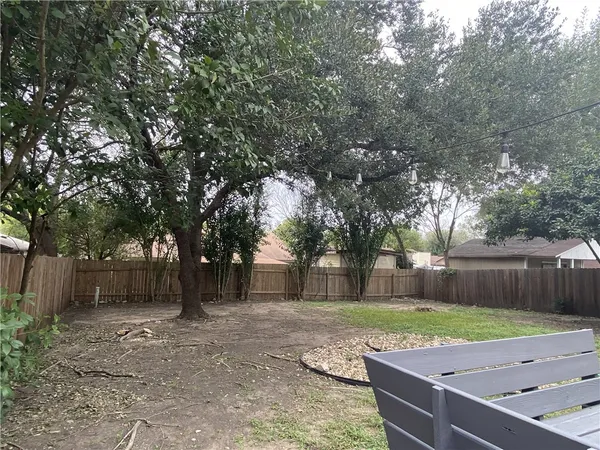 a view of a backyard with large trees and wooden fence
