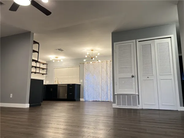 an empty room with wooden floor cabinet and windows