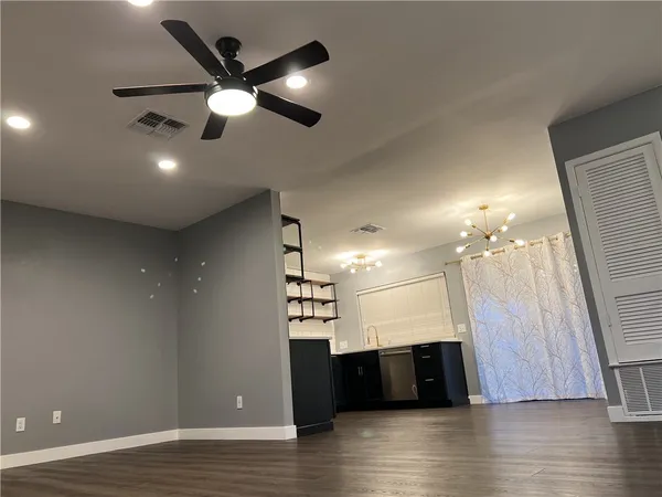 a view of an empty room with wooden floor and a ceiling fan