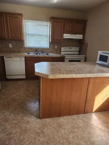 a kitchen with granite countertop a sink a stove and cabinets