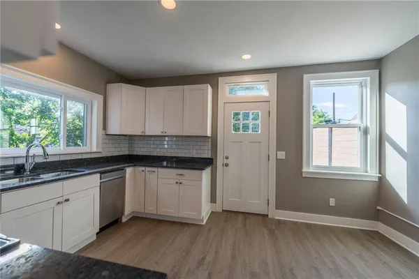 a kitchen with stainless steel appliances granite countertop a stove a sink and white cabinets
