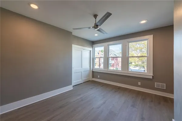 an empty room with wooden floor and a ceiling fan