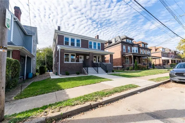 a view of a brick building next to a yard with big trees