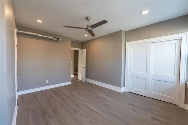 an empty room with wooden floor fan and windows
