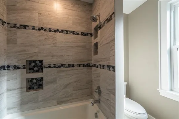a bathroom with a granite countertop toilet and a shower