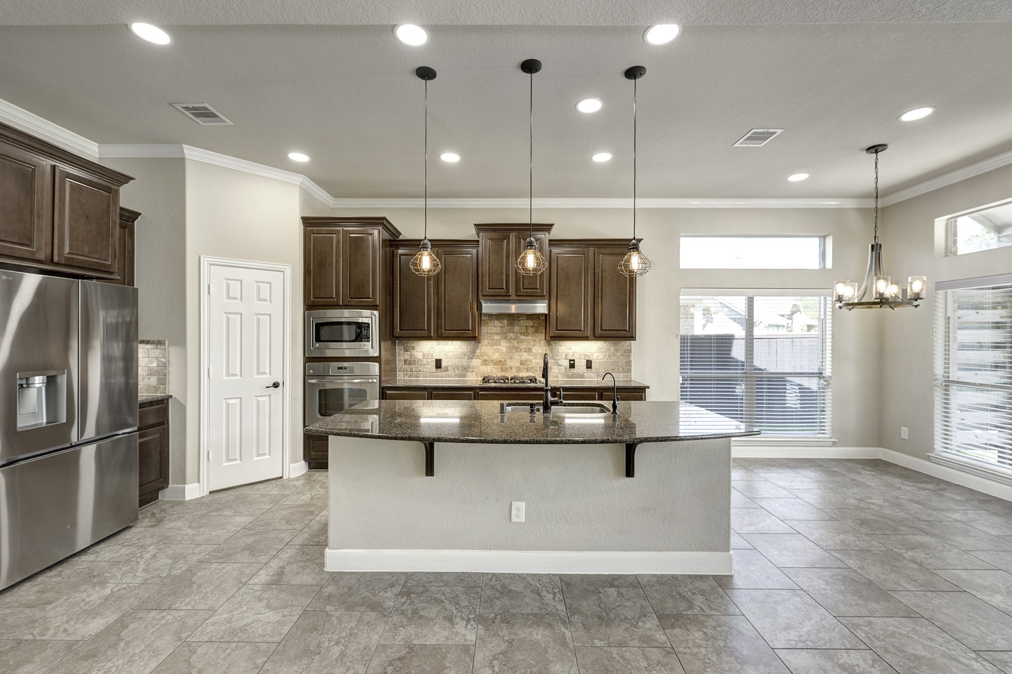 11 Red Wagon Drive Spring, TX 77389 - Photo 9 of 32 The island kitchen has a gas cooktop, modern lighting, travertine backsplash, and a walk-in pantry.
