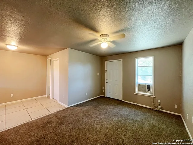 an empty room with chandelier fan and windows