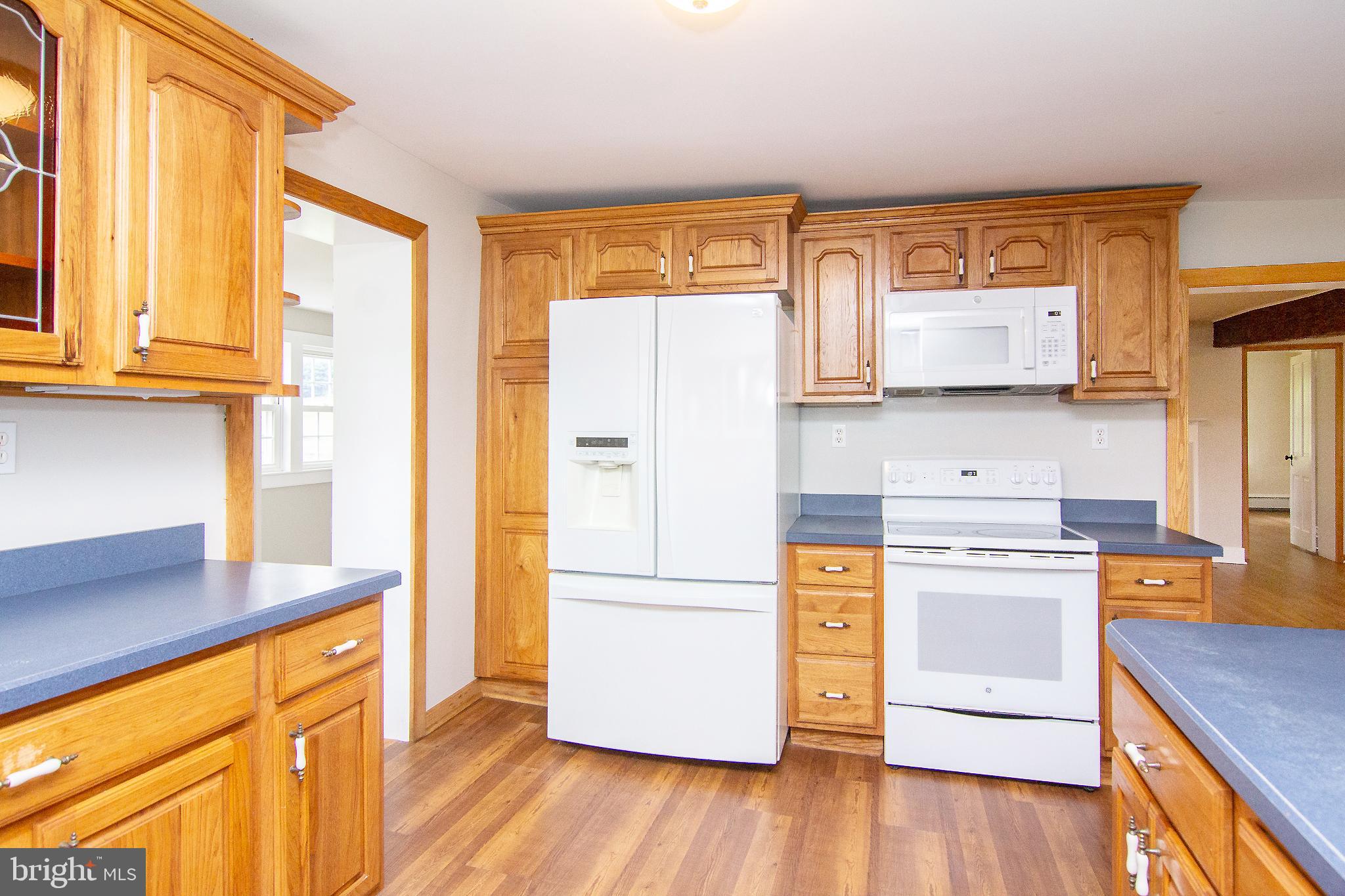 10121 B Clemsonville Road Union Bridge, MD 21791 - Photo 11 of 41 a kitchen with a refrigerator wooden floor and wooden cabinets