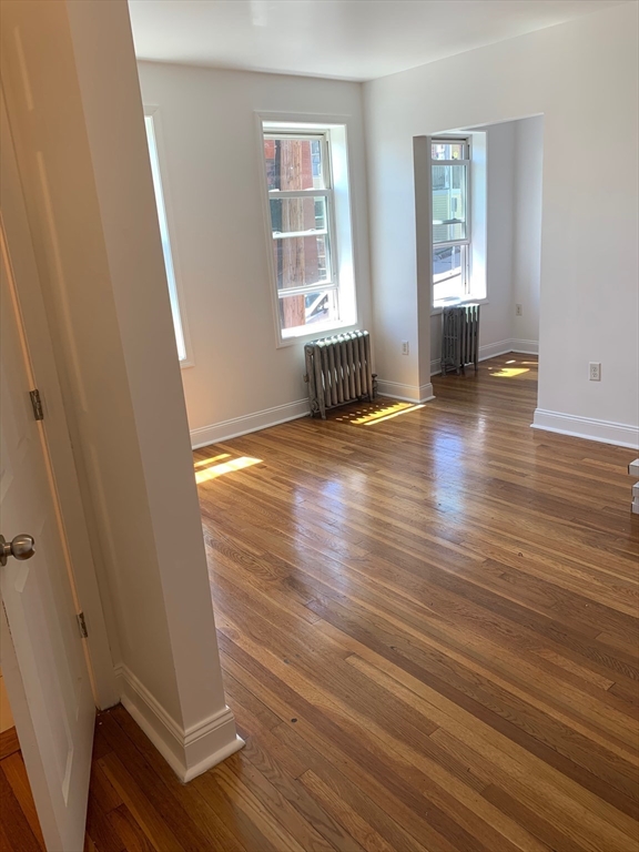 10 Yeamans Street, Unit 121 Revere, MA 02151 - Photo 3 of 8 an empty room with wooden floor and windows