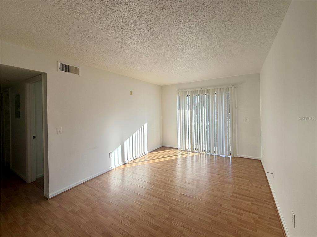 1114 South Pine Ridge Circle, Unit 14 Sanford, FL 32773 - Photo 2 of 10 a view of an empty room with wooden floor and a window