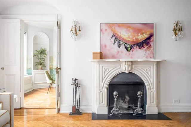 a view of a livingroom with a fireplace potted plants and wooden floor