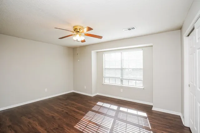a view of an empty room with window and wooden floor