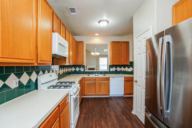 a kitchen with stainless steel appliances granite countertop a refrigerator a stove and a wooden floors