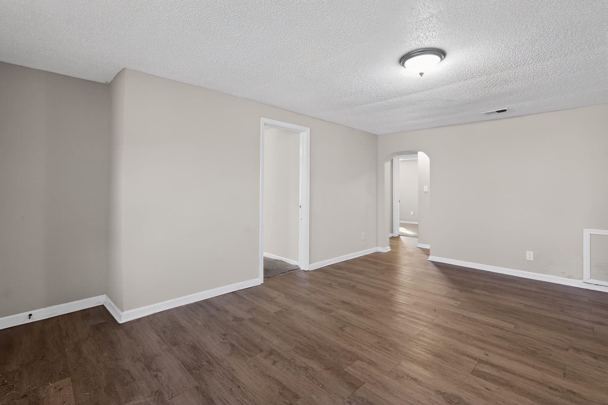4043 Clearpool Circle Road Memphis, TN 38118 - Photo 11 of 33 Spare room featuring arched walkways, a textured ceiling, and dark wood finished floors