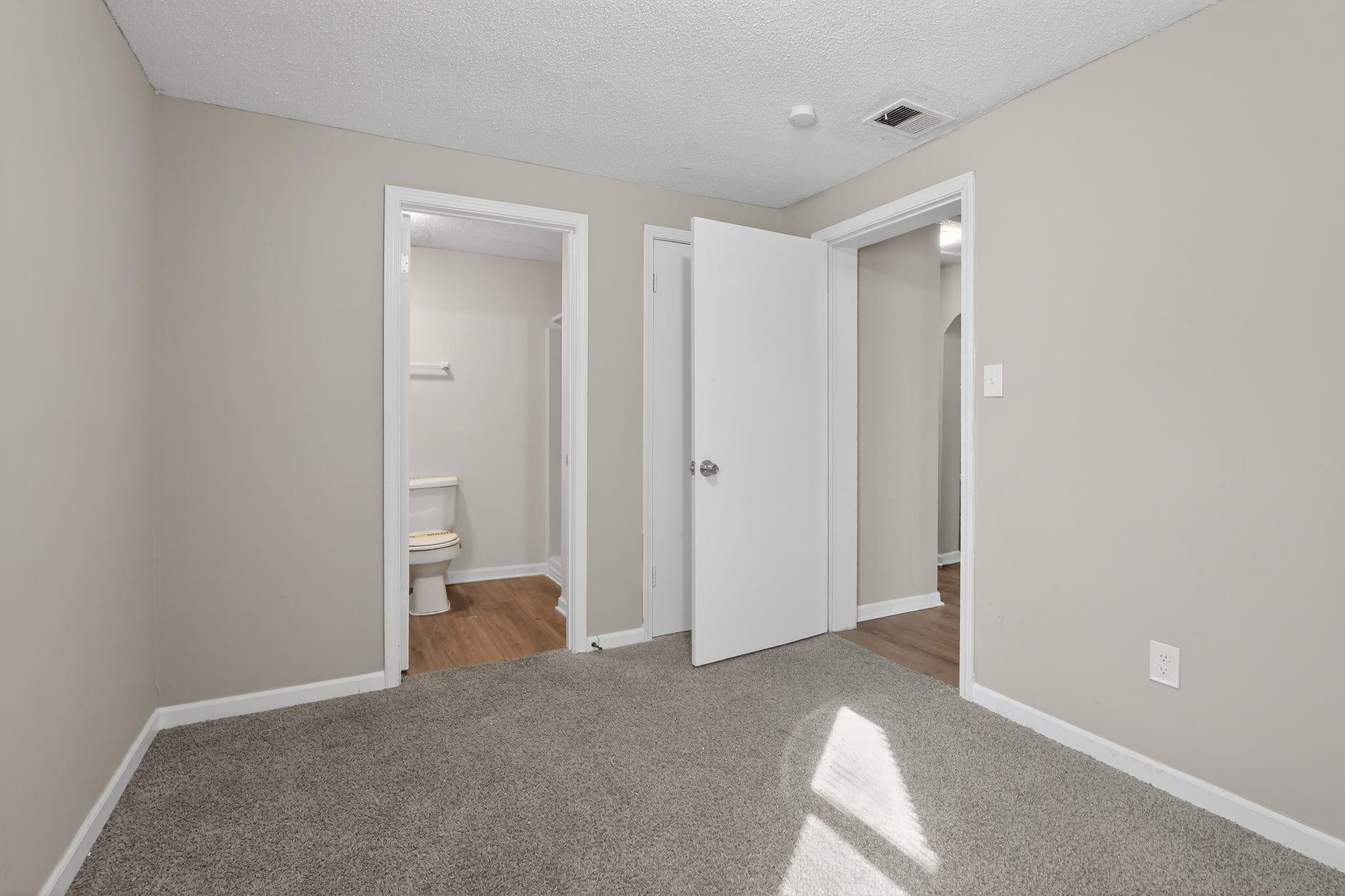 4043 Clearpool Circle Road Memphis, TN 38118 - Photo 29 of 33 Unfurnished bedroom featuring a textured ceiling, light carpet, ensuite bath, and arched walkways
