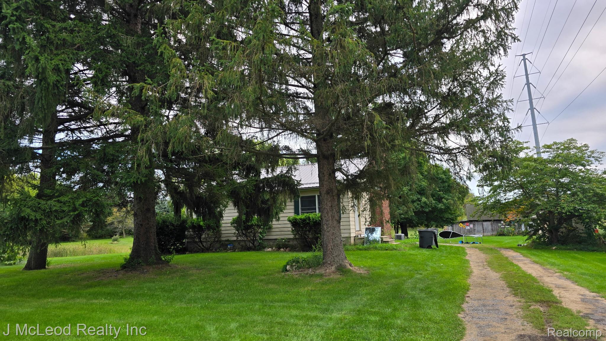 69 West Snover Road Mayville, MI 48744 - Photo 42 of 46 Expansive green lawn with mature evergreen trees and a gravel drive