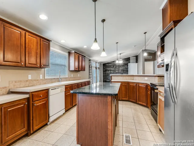 a kitchen with stainless steel appliances granite countertop a sink a stove and a refrigerator