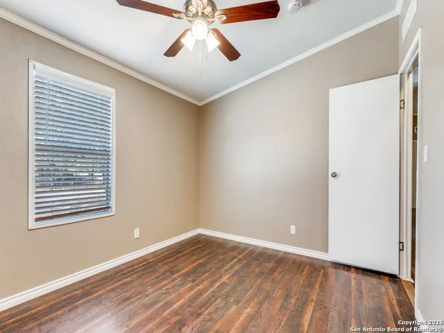 a view of an empty room with wooden floor and a window
