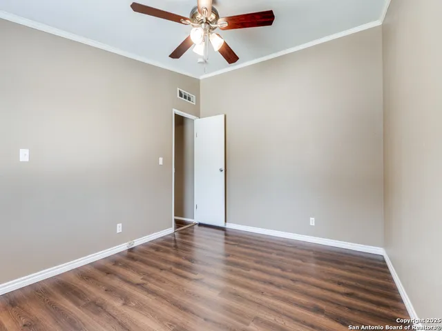 an empty room with wooden floor chandelier fan and closet area