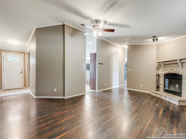 an empty room with wooden floor a fireplace and windows