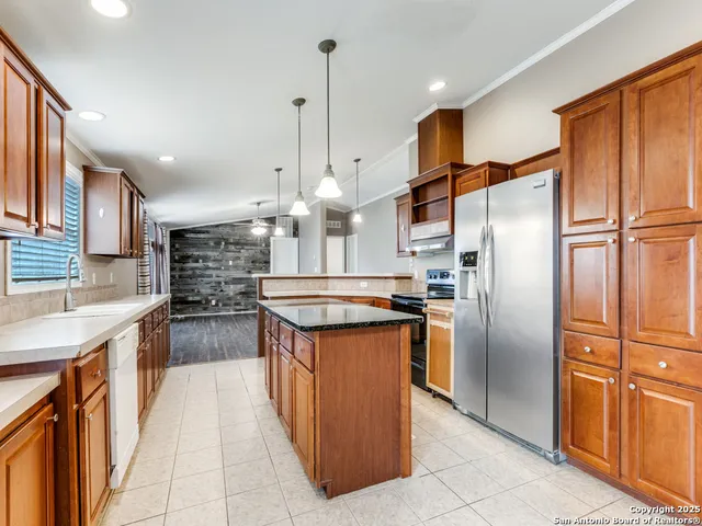 a kitchen with stainless steel appliances granite countertop a refrigerator a sink and a stove