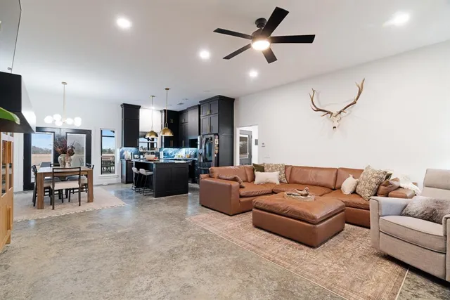 a living room with furniture kitchen view and a chandelier