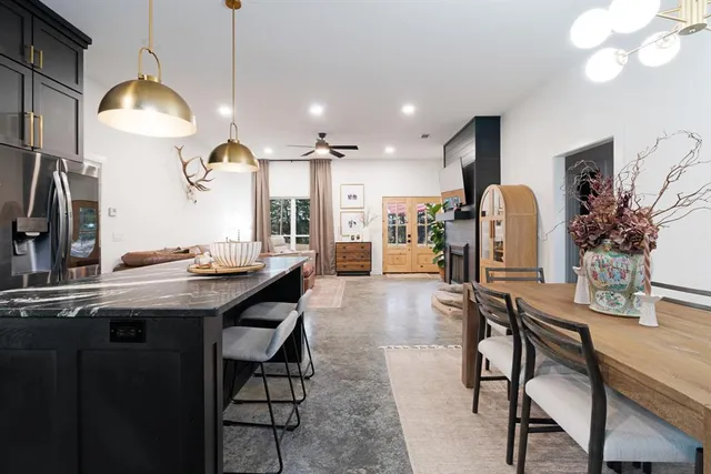 a kitchen with stainless steel appliances kitchen island granite countertop a table chairs refrigerator and sink