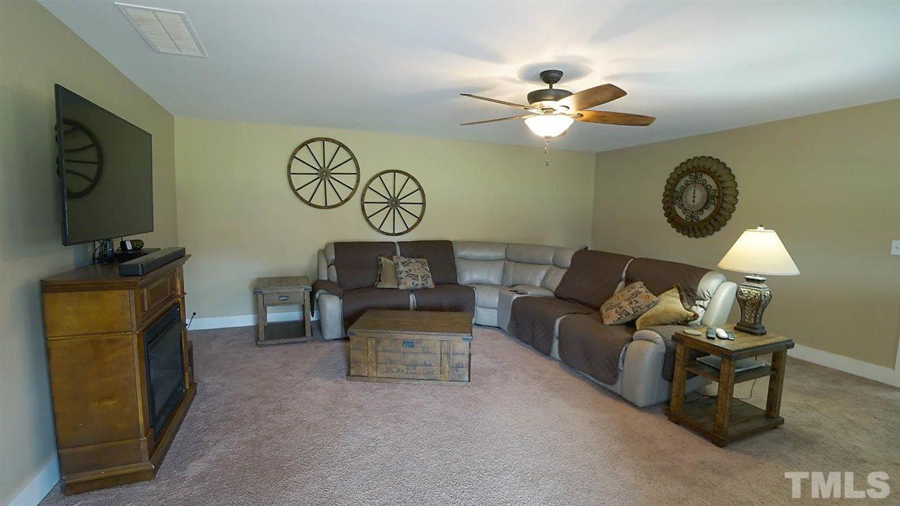1173 Tant Road Spring Hope, NC 27882 - Photo 22 of 26 a living room with furniture a clock and a flat screen tv