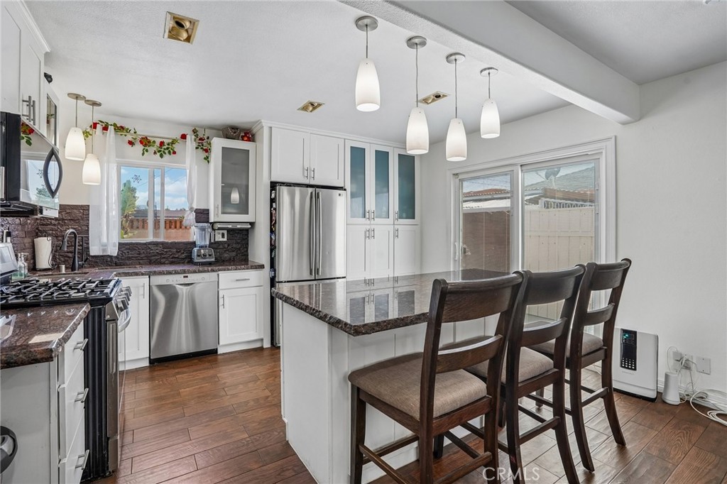 6412 Shawnee Road Westminster, CA 92683 - Photo 7 of 36 a kitchen with stainless steel appliances kitchen island granite countertop a table chairs and a refrigerator