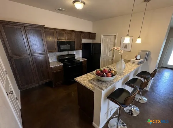 a kitchen with a refrigerator a stove a sink dishwasher a dining table and chairs with wooden floor