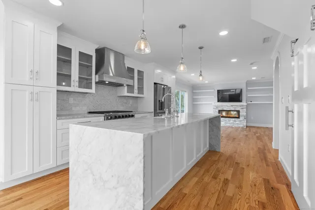 a large kitchen with stainless steel appliances kitchen island a large counter top a stove and a wooden floors