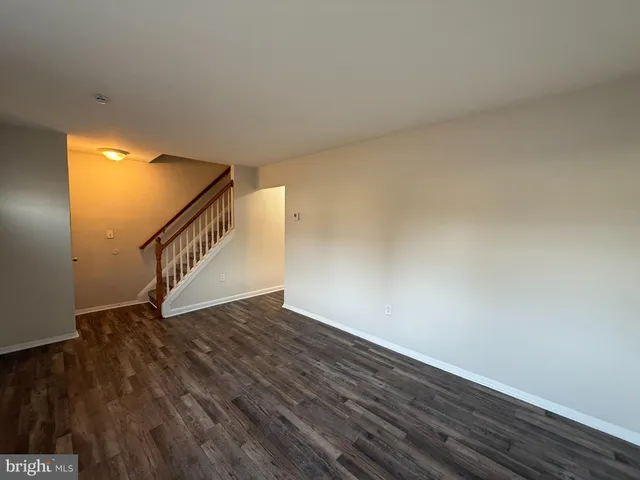 a view of an empty room with wooden floor and stairs